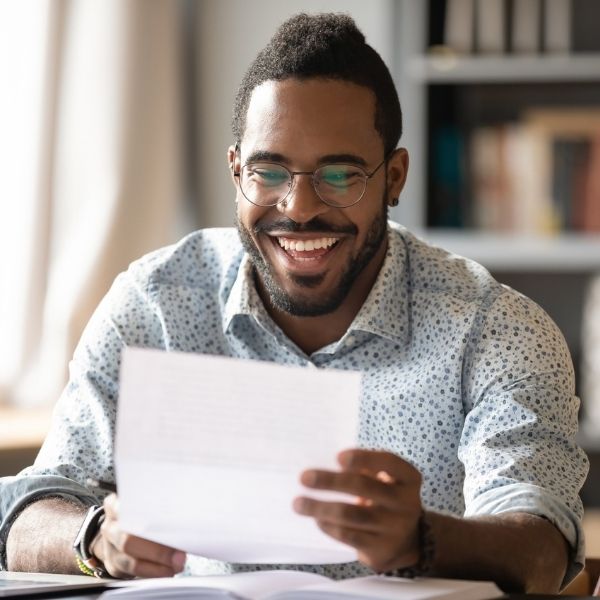 man smiling while looking at paper